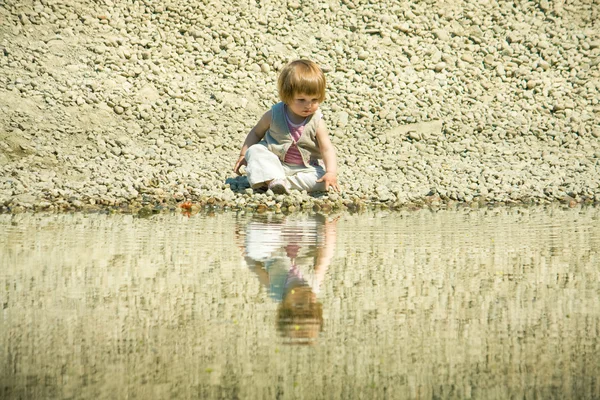 小女孩坐在一个石头海滩上 — 图库照片