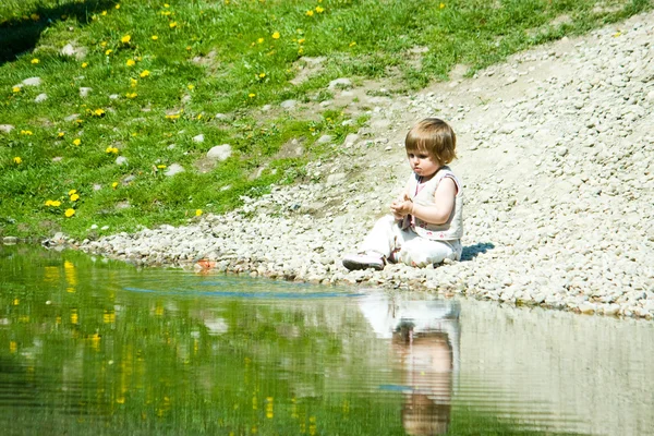 Маленькая девочка, сидящая на каменном пляже — стоковое фото