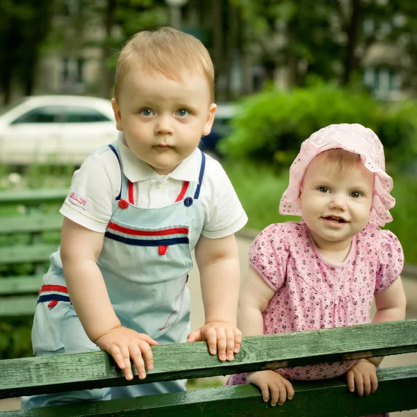 Niño y niña en el banco en el parque —  Fotos de Stock