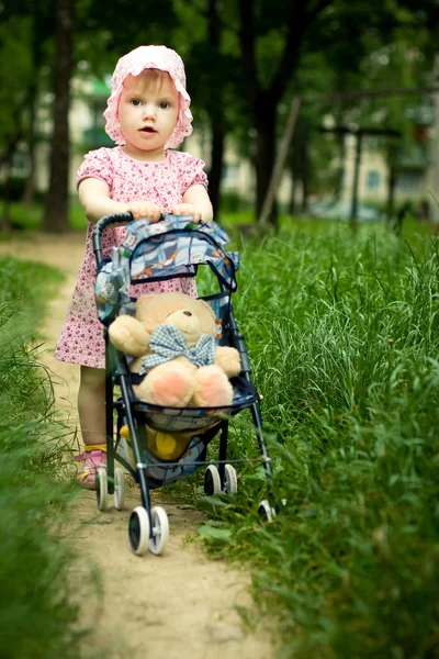 Meisje met teddy beer in wandelwagen — Stockfoto