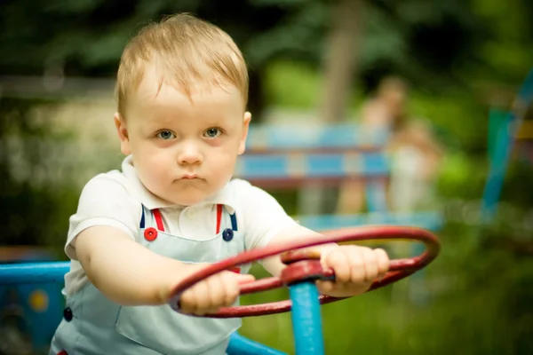 Junge spielt mit einem Rad auf Spielplatz — Stockfoto