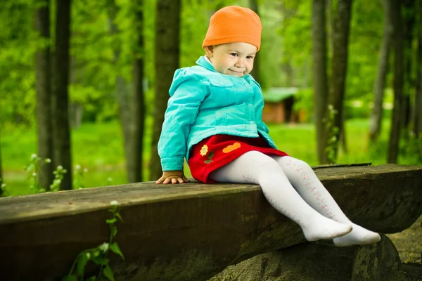 Bambino seduto su una panchina di legno — Foto Stock