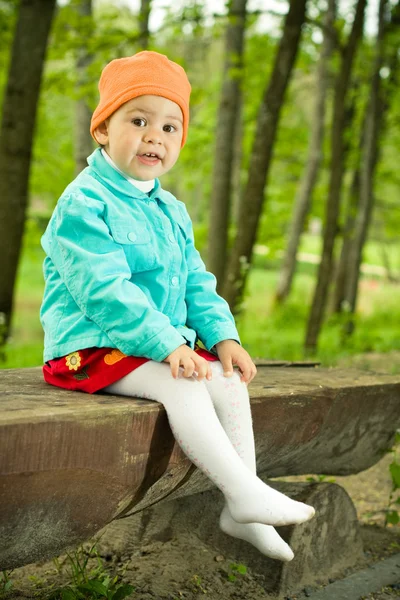 Bebé joven se sienta en un banco de madera —  Fotos de Stock
