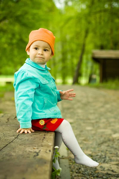 Young baby sits on a wooden bench — Stock Photo, Image