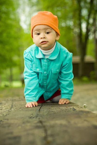 Jovem bebê senta-se em um banco de madeira — Fotografia de Stock