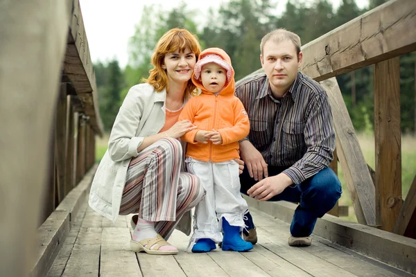 Família feliz em uma ponte de madeira — Fotografia de Stock