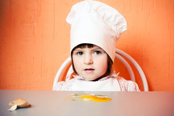 Mladá kuchařka s rozbité vajíčko — Stock fotografie