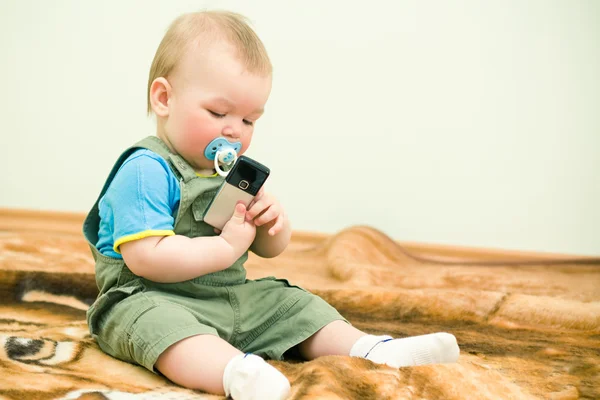 Baby ziet er op mobiele telefoon met belangstelling — Stockfoto