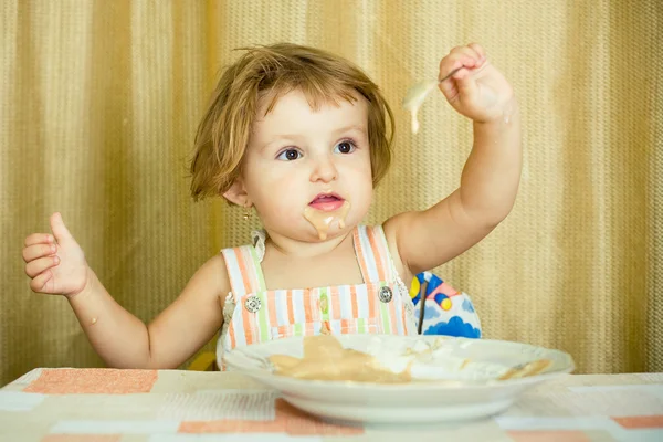 Little girl plays with porridge — Stock Photo, Image