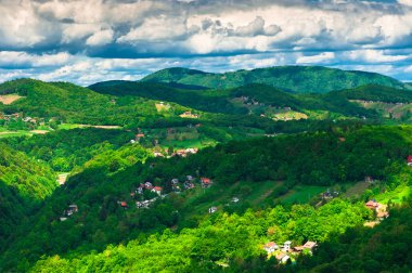 Dramatic clouds over green hills clipart