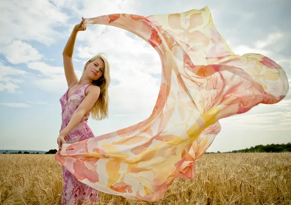 The young woman in the field holding scarf to wind. — Stock Photo, Image