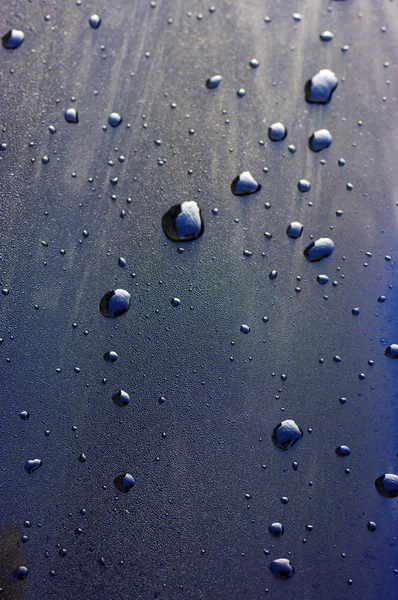 Gotas de agua sobre negro con reflejo en el cielo — Foto de Stock