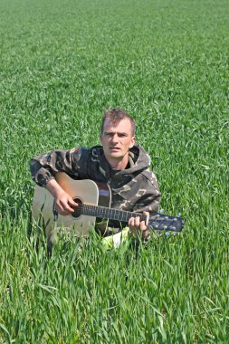 Man in a field with a guitar clipart