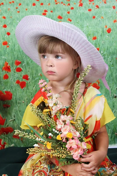 Menina bonita em um chapéu com flores silvestres — Fotografia de Stock