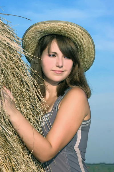 stock image Beautiful girl in a straw hat near haystacks