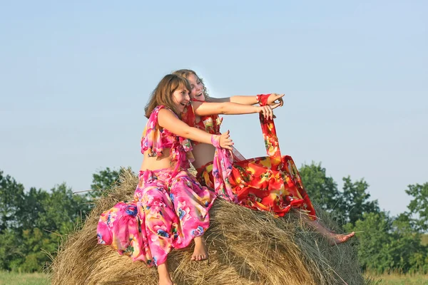 Two beautiful girls in bright dresses from top haystacks — Stock Photo, Image