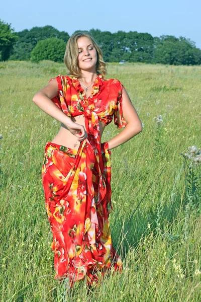Blonde in a bright dress dancing in a field — Stock Photo, Image