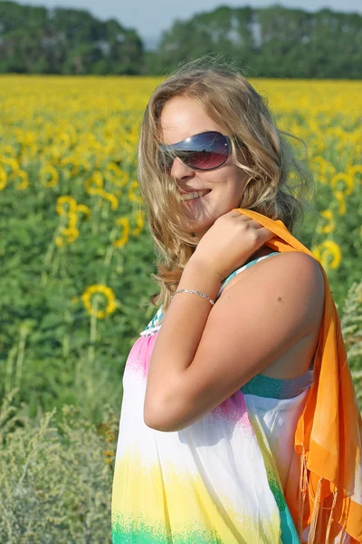 Blonde in sunglasses against the backdrop of sunflowers — Stock Photo, Image