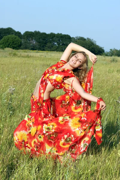 Blonde in a bright dress dancing in a field — Stock Photo, Image