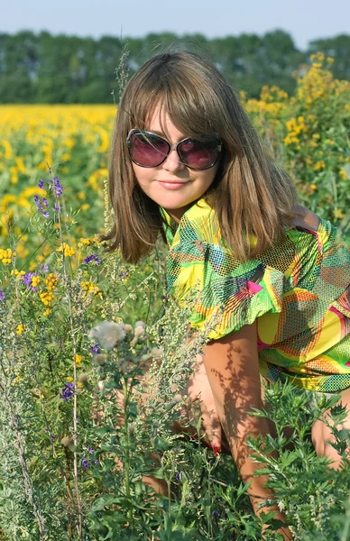 Brunette in sunglasses against the backdrop of sunflowers — Stock Photo, Image