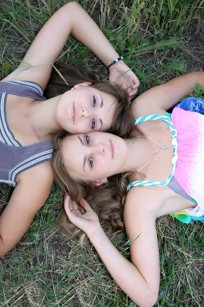 Two girls lying on the grass and look at the sky — Stock Photo, Image