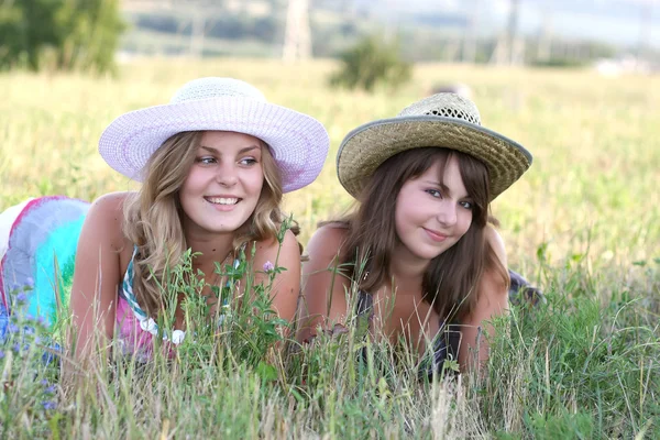 모자에 두 여 자가 잔디에 누워 — 스톡 사진