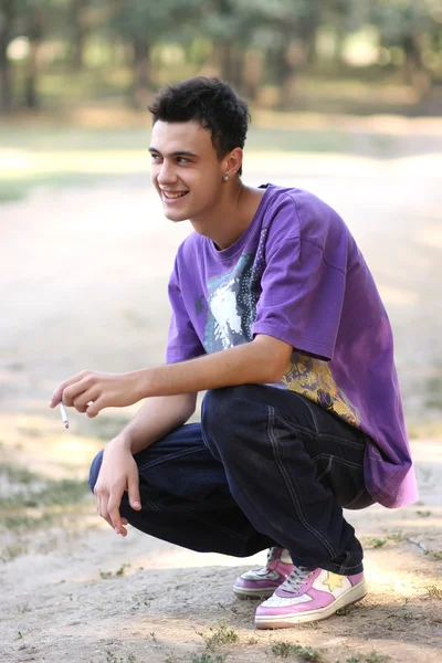 Jonge man in een Lila shirt met een sigaret — Stockfoto
