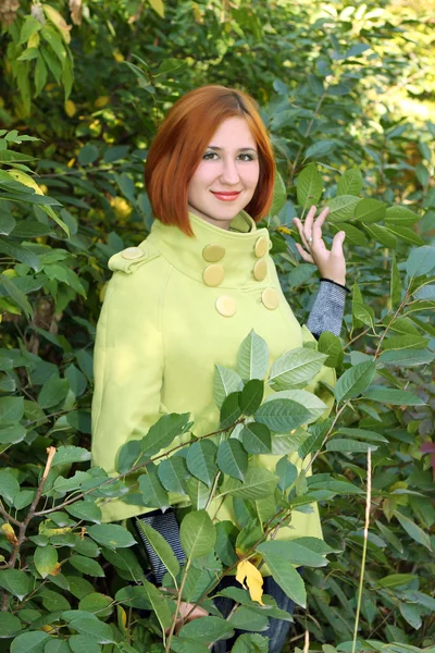 Beautiful girl in a light-green coat on green background — Stock Photo, Image