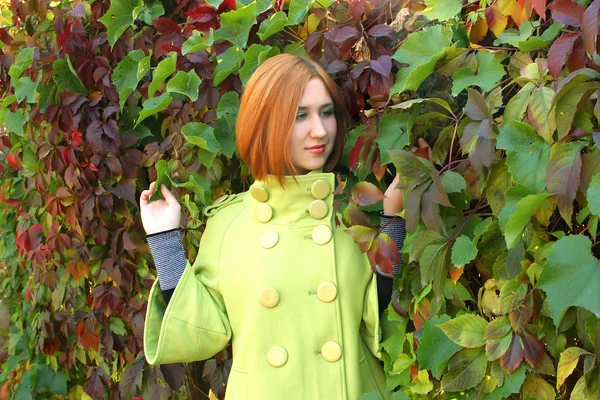 Krásná dívka ve světle zeleném kabátě na pozadí Thickem — Stock fotografie