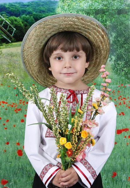 Handsome boy in a straw hat with a bouquet of wildflowers — Stok fotoğraf