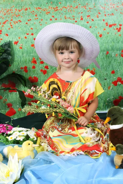 Bella ragazza in un abito luminoso e un cappello su un campo di sfondo — Foto Stock