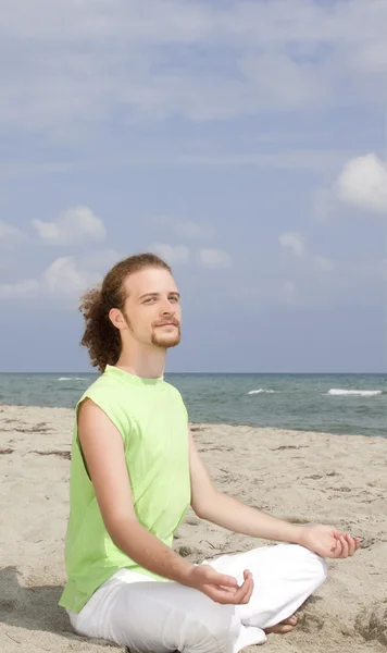 Мужчина медитирует на пляже — стоковое фото
