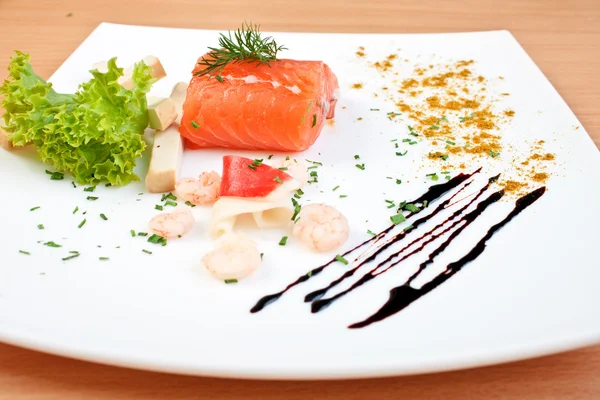 Вкусный лосось на тарелке, украшенной салатным сыром и морепродуктами — стоковое фото