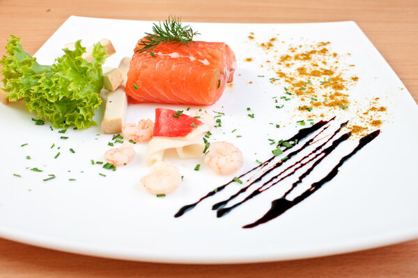Delicious salmon on plate decorated with salad cheese and seafoo
