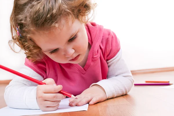Kleines Mädchen zeichnet um ihre Hand — Stockfoto