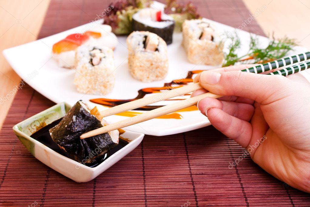 Holding sushi roll with chopsticks