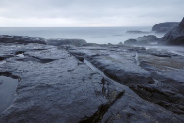 Rocks with a calm blue sea clipart