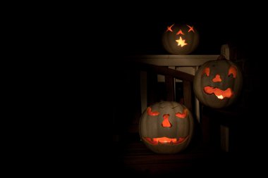 Three lit white jack o-lanterns on a bench clipart