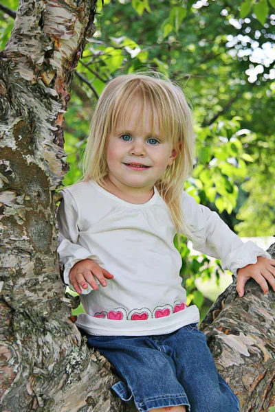Malá holka sedí na stromě — Stock fotografie