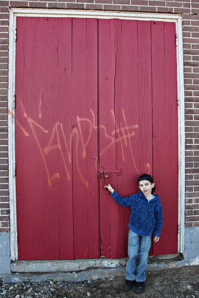 Young child hanging out near a grungy wall — Stock Photo, Image