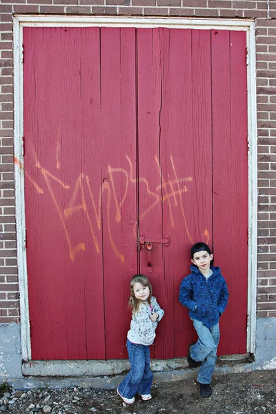 Crianças pequenas penduradas perto de uma parede grungy — Fotografia de Stock