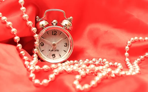 Hours and beads on a white red satiny ba — Stock Photo, Image