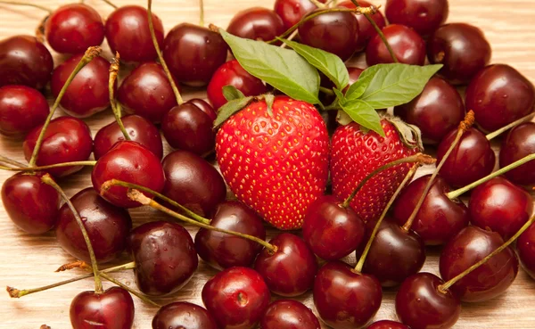 Hintergrund aus einer Süßkirsche und zwei Erdbeeren — Stockfoto