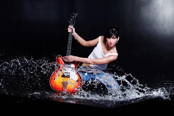 Rock-n-roll girl playing a guitar in water on black — Stock Photo, Image