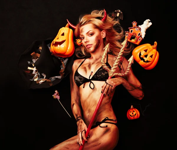 Beautiful devil with trident and Halloween accessories on black Royalty Free Stock Photos