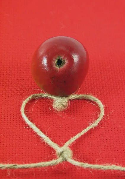 Pomme rouge et ficelle en forme de coeur — Photo