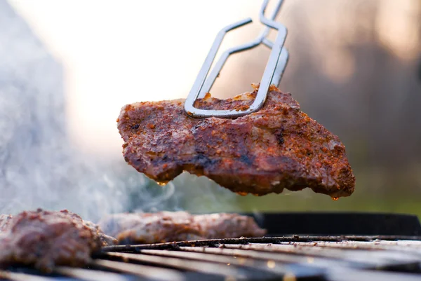 Bbq closeup with metal tongs Royalty Free Stock Images