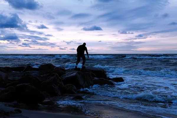 Человек, стоящий на каменистом берегу моря — стоковое фото