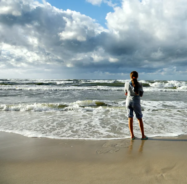 Молодая девушка смотрит в бурное море — стоковое фото