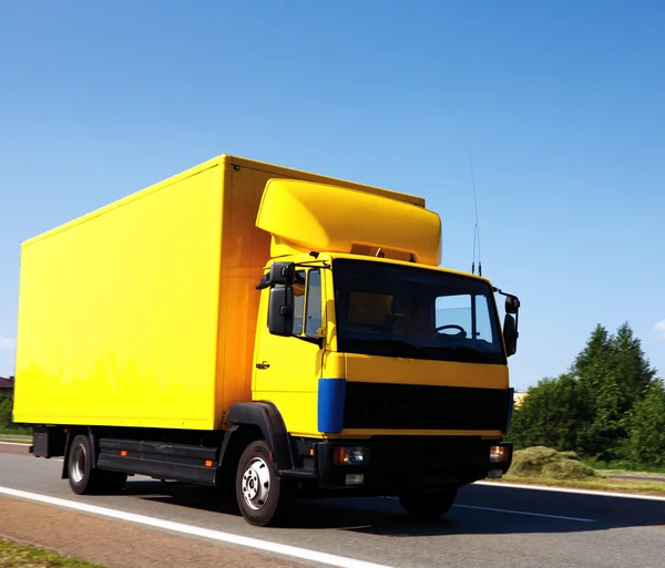 Gelber LKW unterwegs unter blauem Himmel — Stockfoto